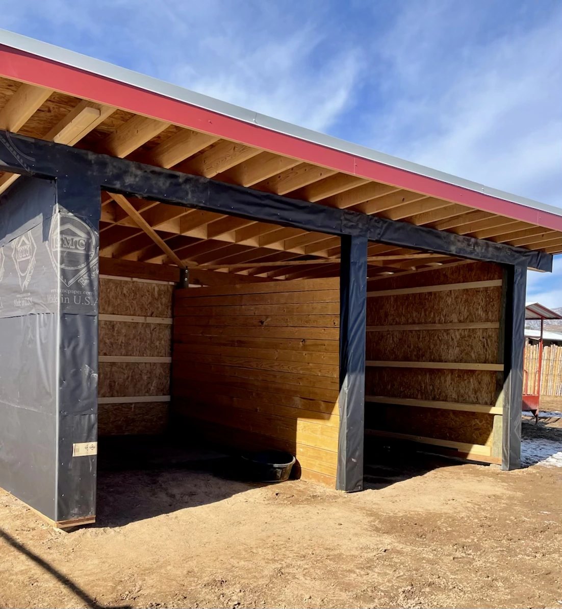 A run-in shelter under construction with a red metal roof