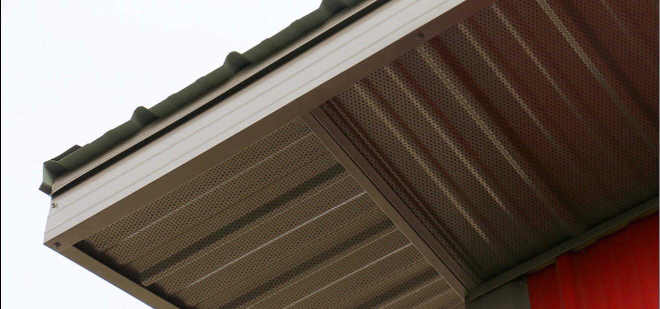Perforated metal soffit and metal fascia along a metal roof edge